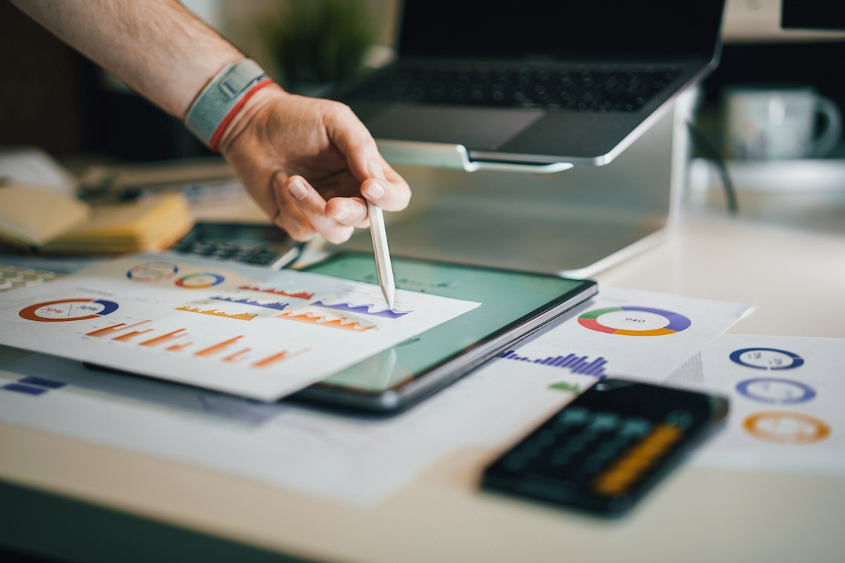 Hand pointing a stylus at financial charts and a business report